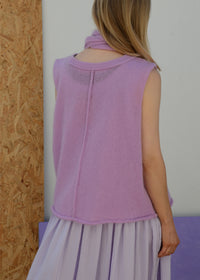 Woman wearing a light purple sleeveless knitted top and skirt against a plain background